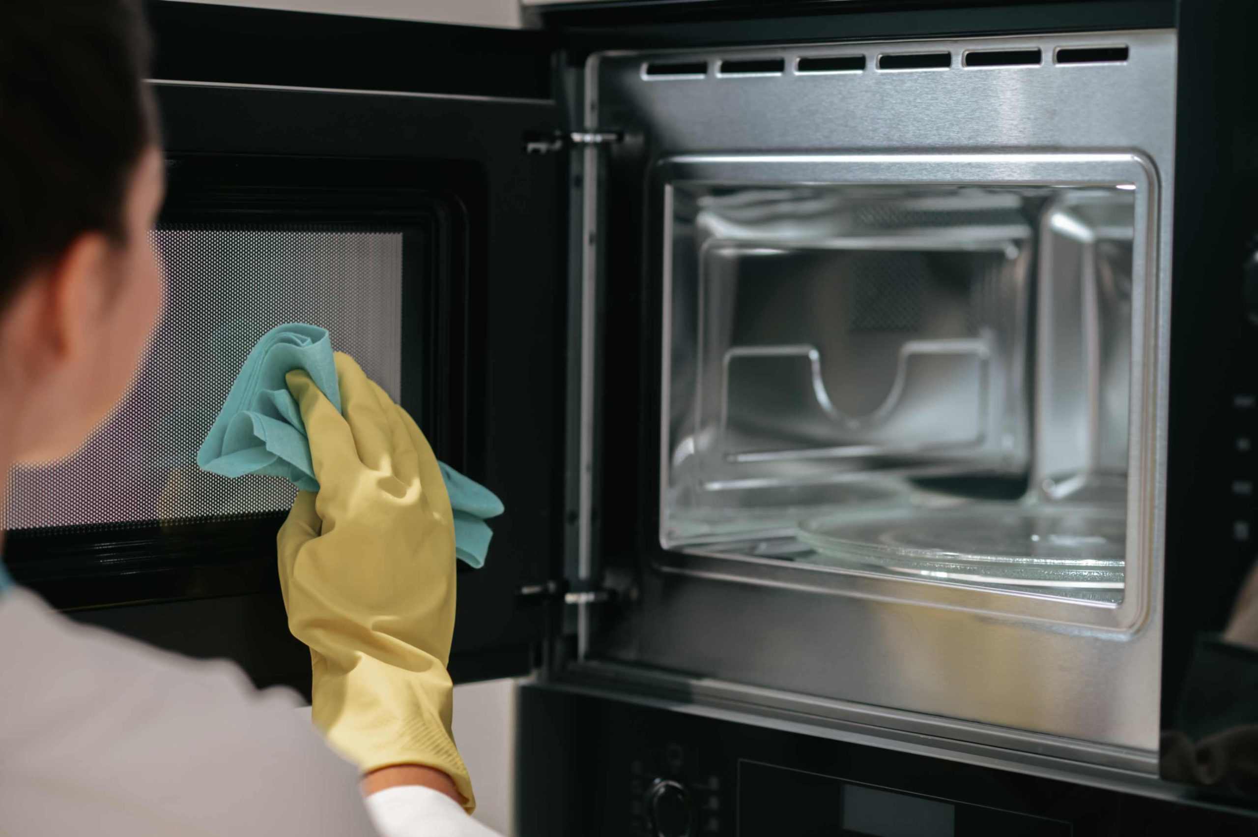 an image displaying a person cleaning a microwave.